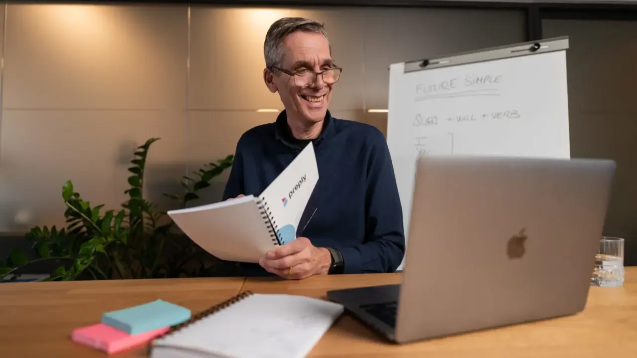 Lehrer erklärt **adjektive und adverbien englisch** mit einem Flipchart und Notizbuch.