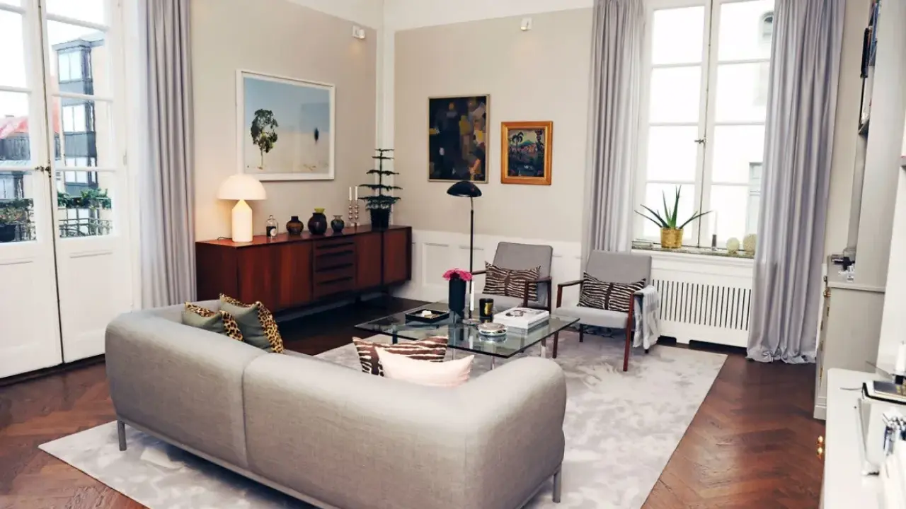 Ett modernt vardagsrum med en grå soffa, glasbord och konst. Johan Pråmell skulle trivas här.