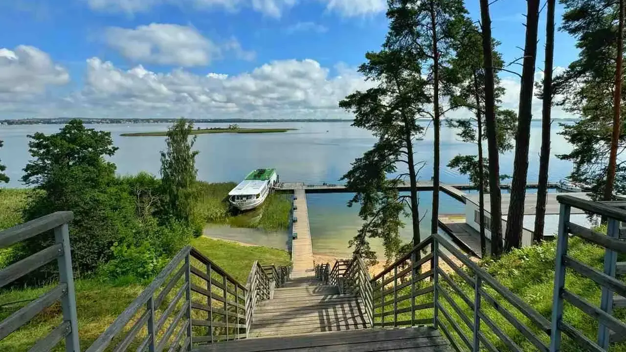 Drewniane schody prowadzą do jeziora, gdzie cumuje statek. Idealne miejsce, by zapytać: gdzie na Mazury?