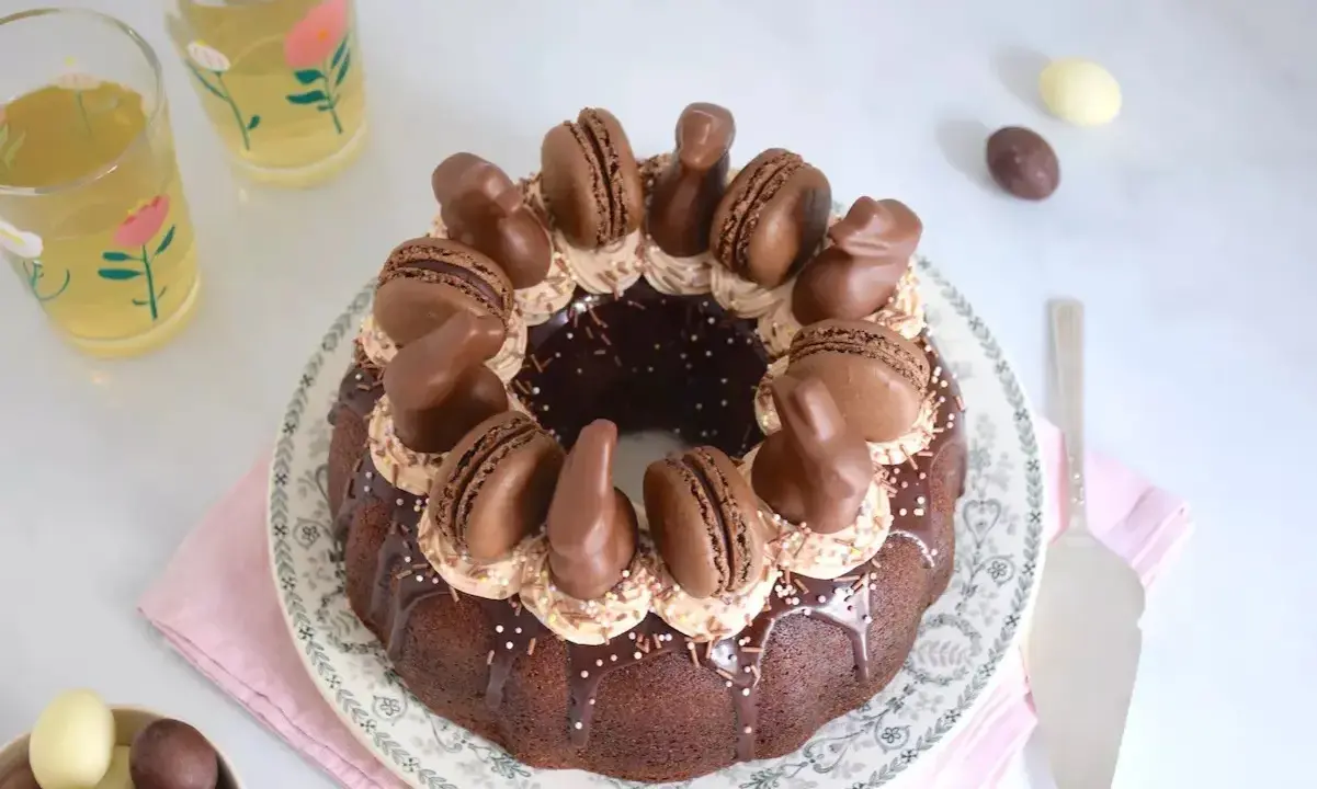 Gâteau rond au chocolat, décoré de macarons, de lapins en chocolat et d'une ganache carambar onctueuse.