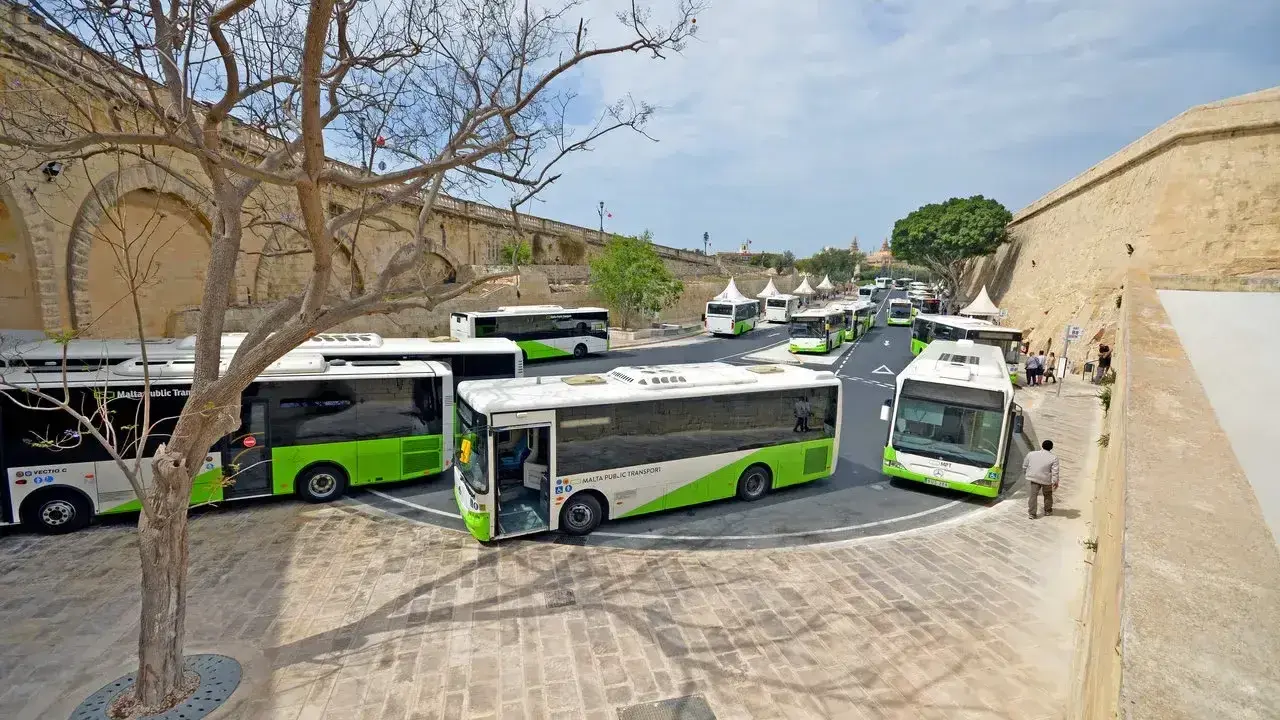 Kolejka zielono-białych autobusów Malta Public Transport czeka na pasażerów. Lotnisko na Malcie tętni życiem.