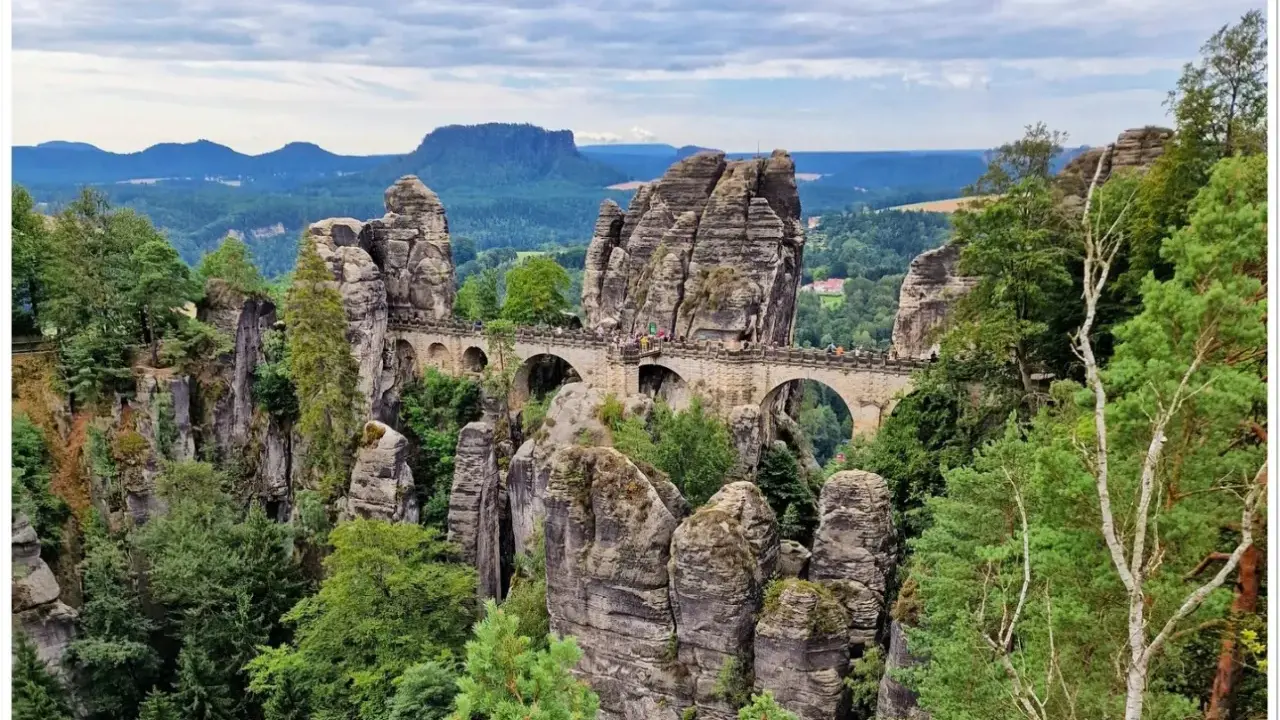 Kamienny most Basteibrücke w Szwajcarii Saksońskiej, łączący skalne baszty pośród zielonych lasów i malowniczych krajobrazów.