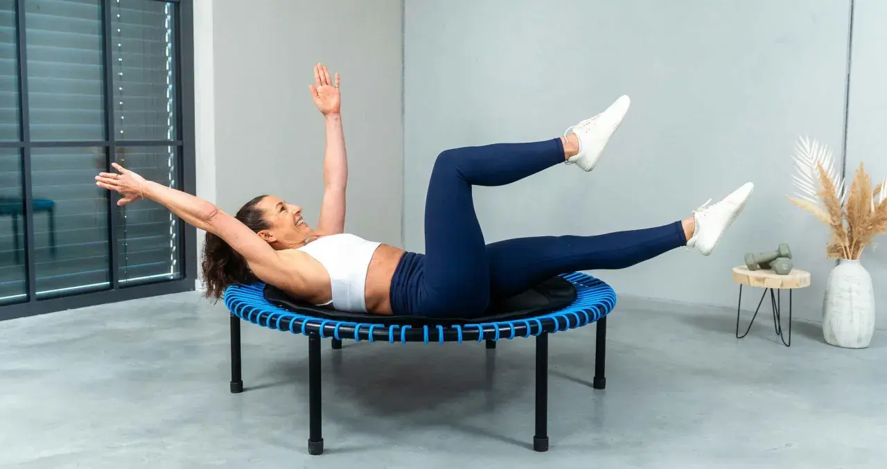Frau macht ein intensives Workout auf einem Trampolin. Sie trainiert ihren Bauch, eine Übung, die man auch bei Tabata machen kann.