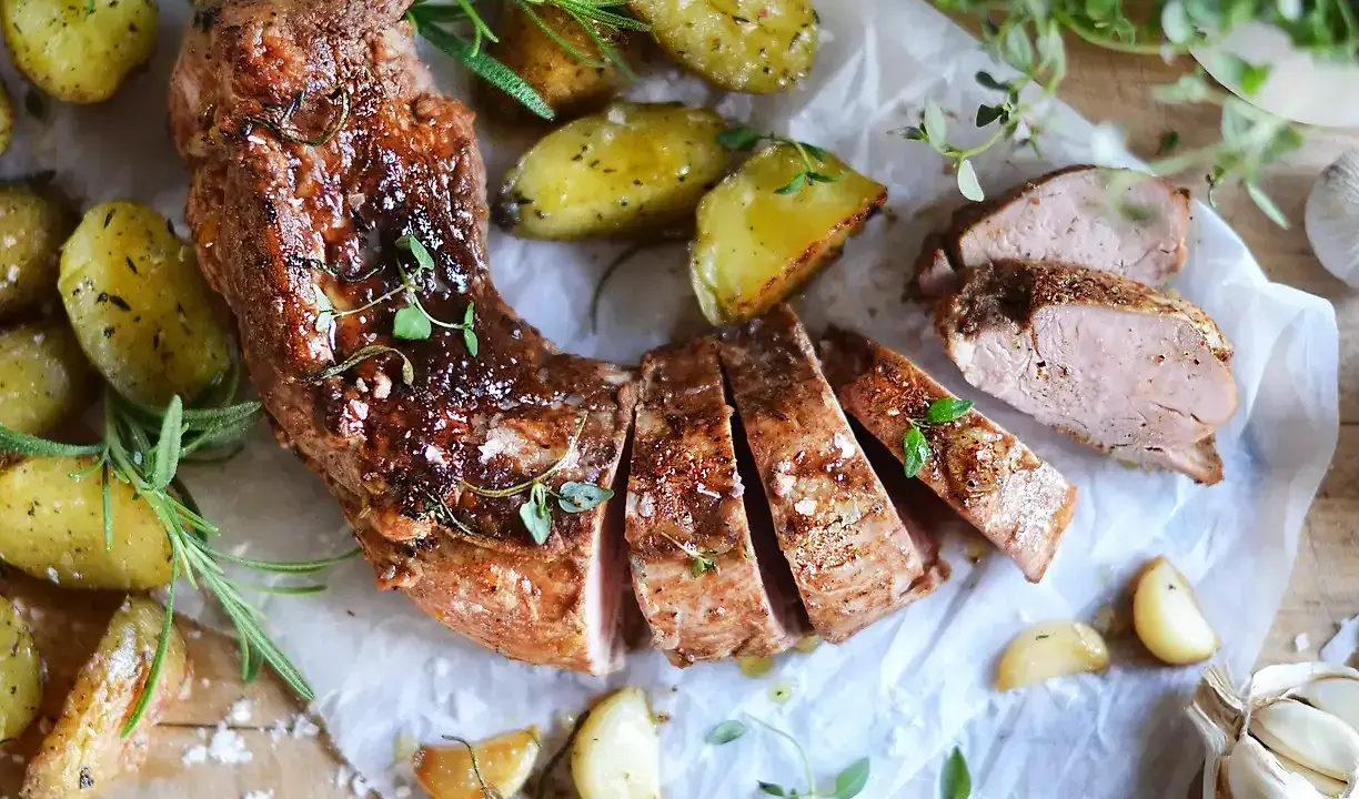 En saftig ytterfile i ugn, skuren i skivor, serverad med ugnsrostade potatisar, vitlök och färska örter.