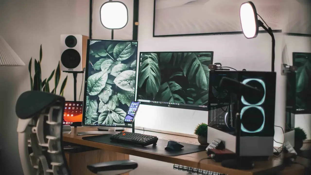 Escritorio moderno con doble monitor, PC con luces RGB, altavoces y plantas. Ideas para tu habitación gamer.