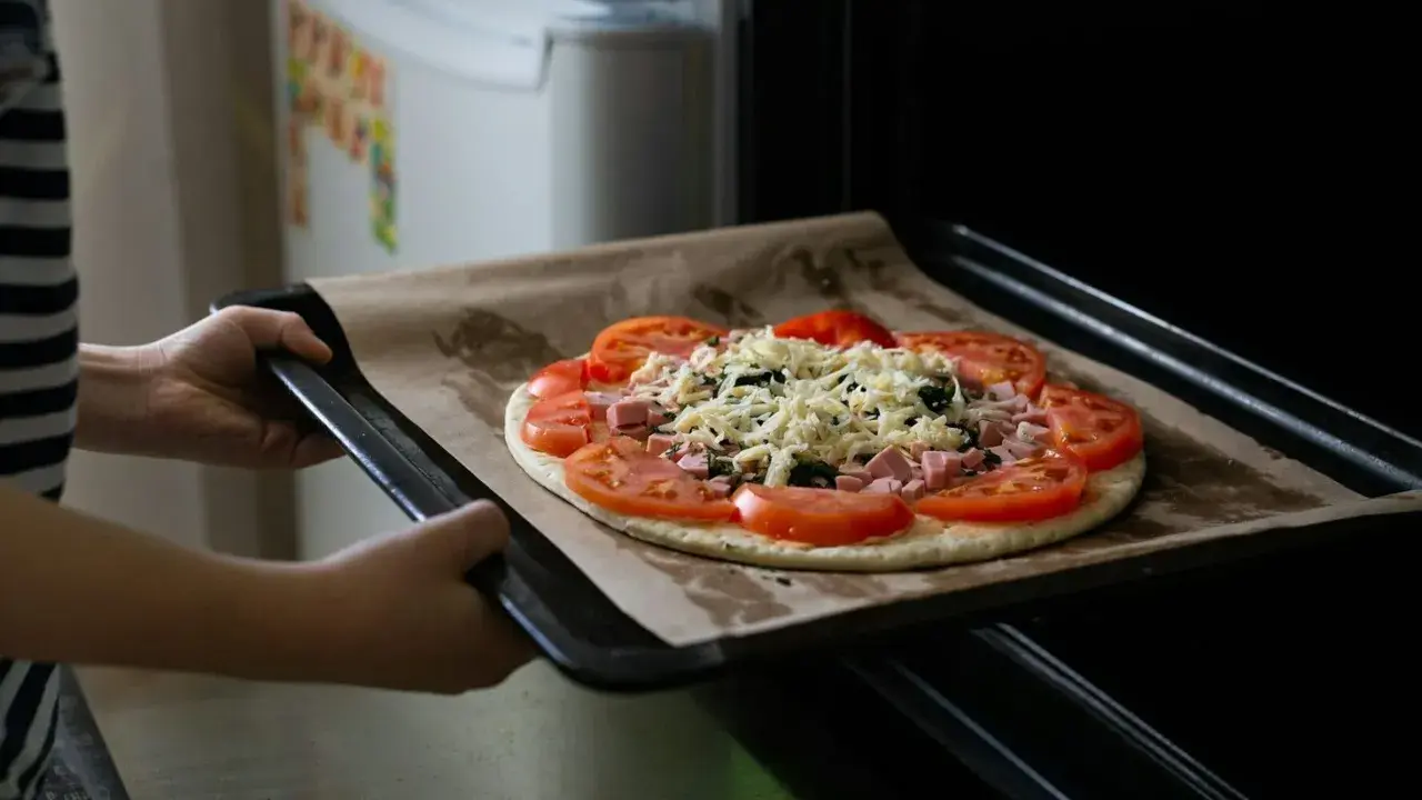 Wkładanie pizzy do piekarnika. Dzięki termoobiegowi ciasto będzie chrupiące, a ser idealnie roztopiony.