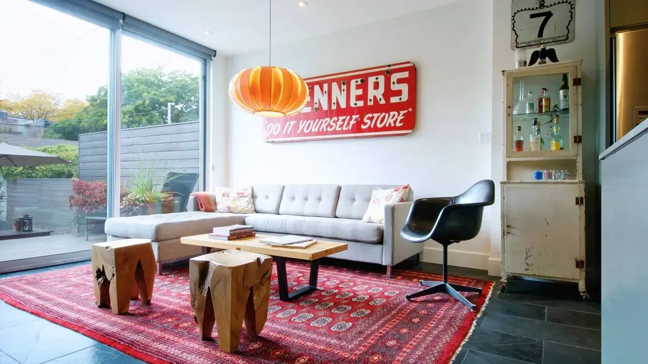 En röd persisk matta ger inspiration till detta vardagsrum med grå soffa, träpallar och en vintage-skylt.