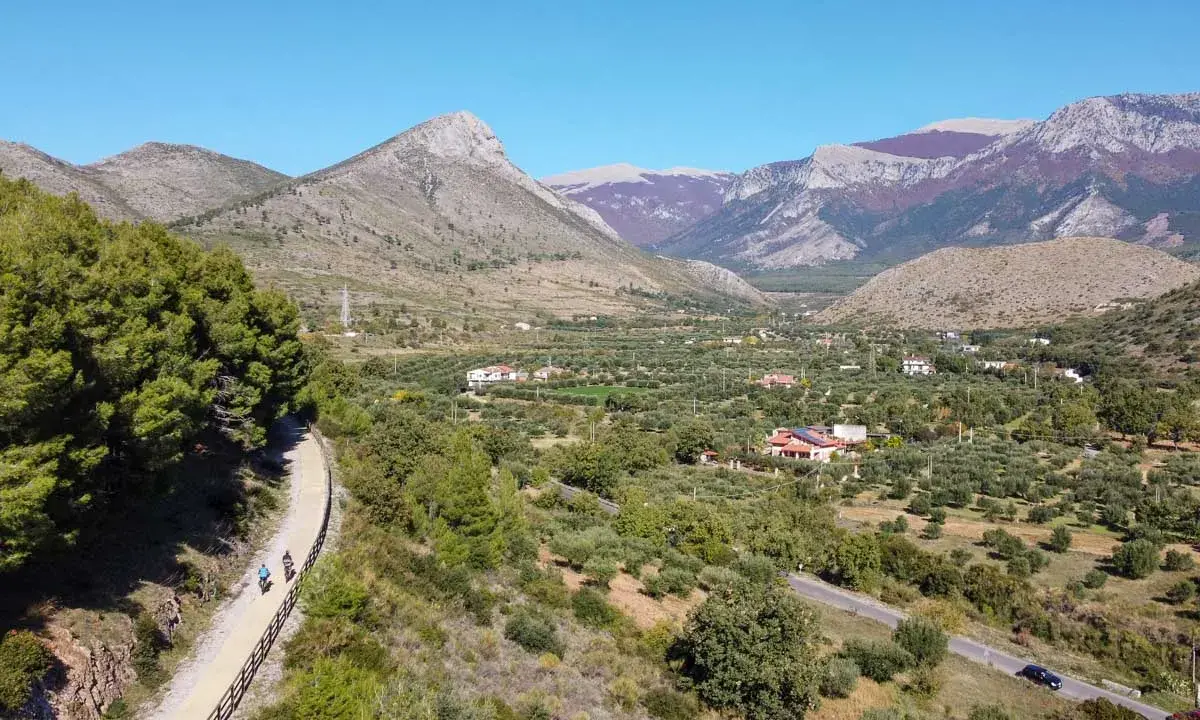 Ciclovia dei parchi Calabria: due ciclisti percorrono un sentiero panoramico tra uliveti e montagne.
