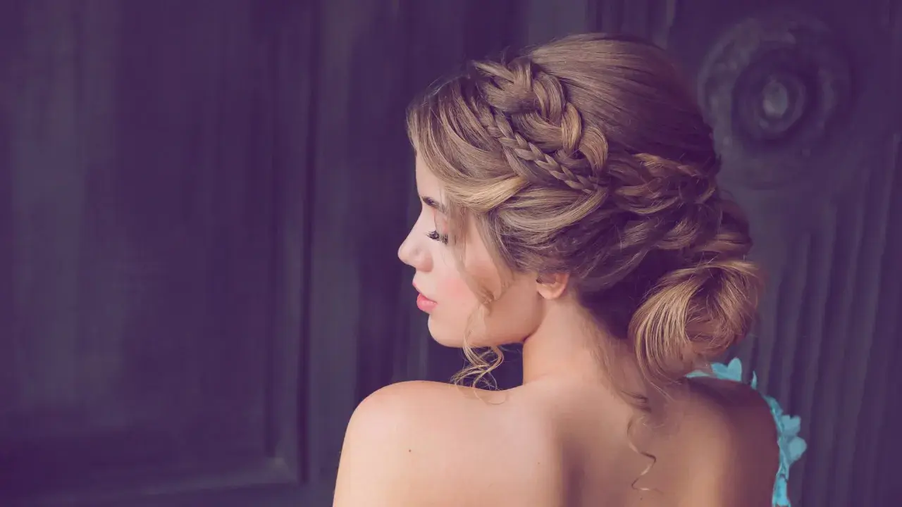 Elegante Frisur für Hochzeitsgäste: Ein kunstvoller Dutt mit geflochtenen Akzenten und zarten Locken.