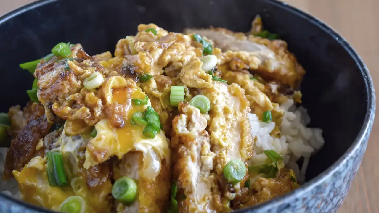 Oishi! Ein dampfendes Schüsselchen mit Reis, bedeckt mit knusprigem Hähnchen, Ei und Frühlingszwiebeln – ein Klassiker der japanischen Rezepte.