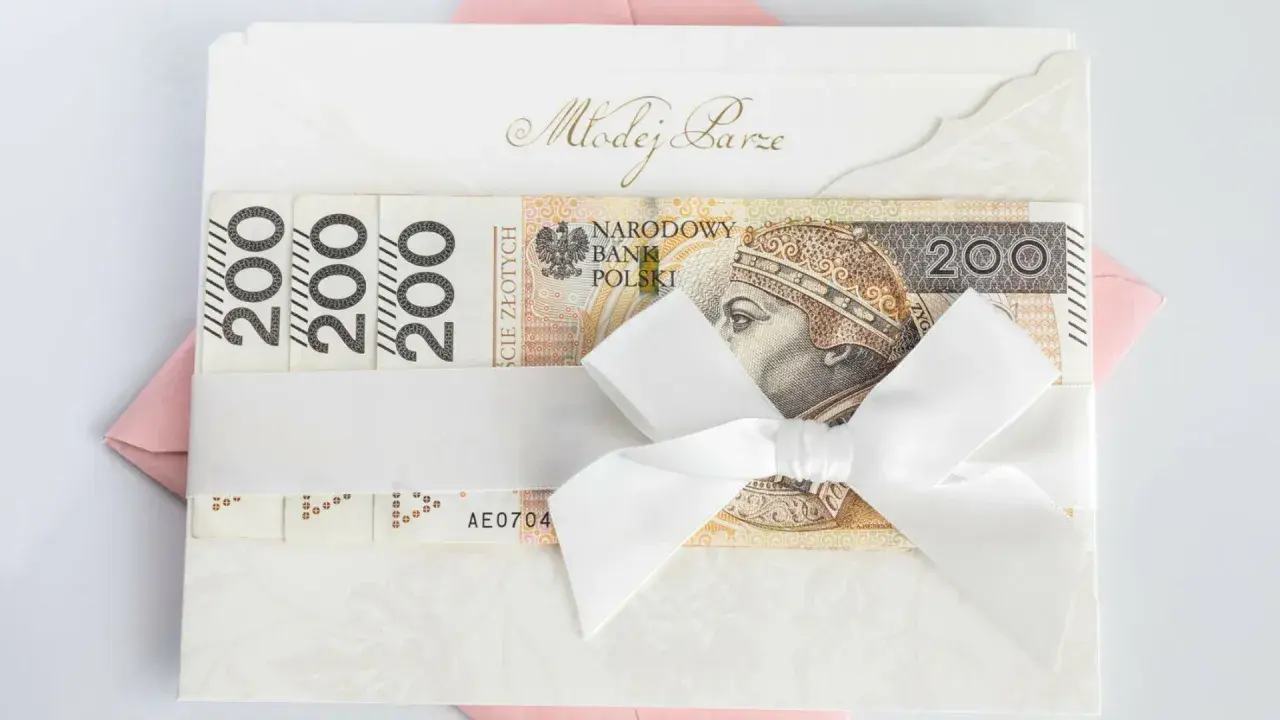 Biała koperta z napisem "Młodej Parze" i banknotami 200 zł. Zastanawiasz się, ile się daje na wesele? Oto inspiracja!