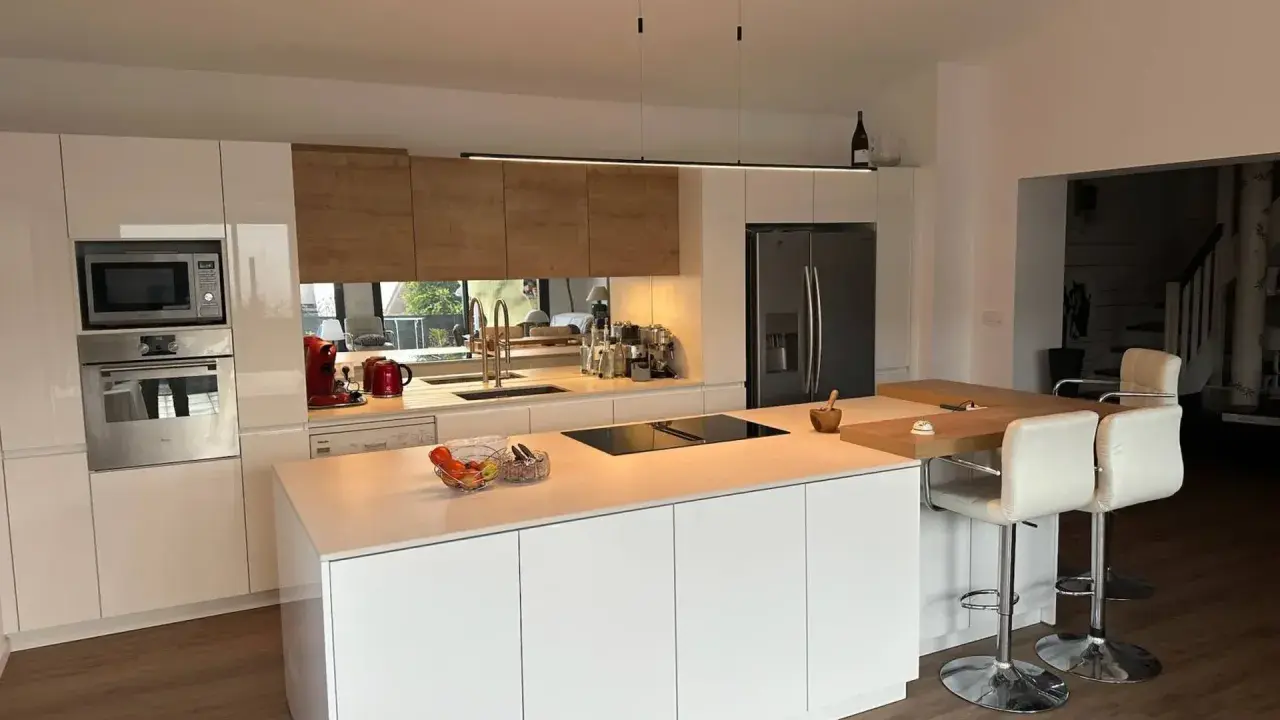 Cuisine moderne et lumineuse, avec îlot central. On y voit la différence entre une cuisine aménagée (meubles) et équipée (électroménager).