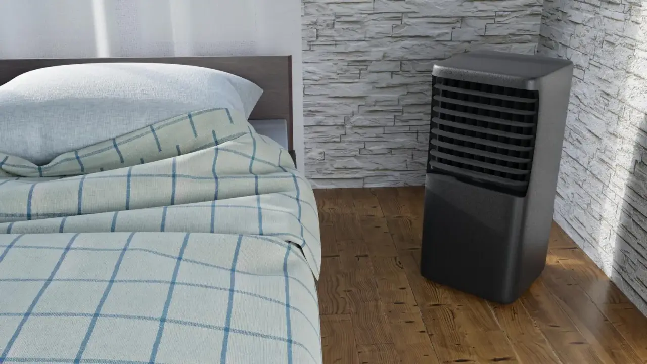 Un aire acondicionado portátil junto a una cama con sábanas a cuadros. ¿Qué es mejor, aire acondicionado portátil o fijo?