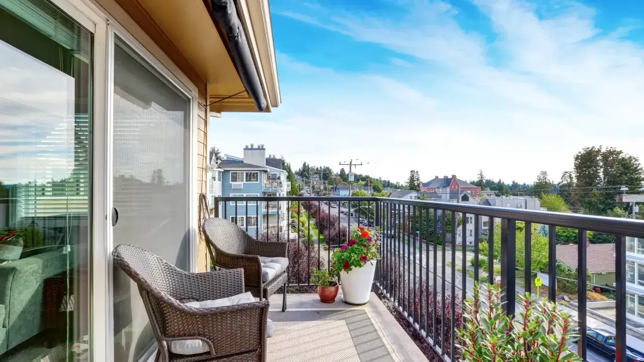 Wygodny balkon z rattanowymi meblami i kwiatami. Inspiracje na płytki na balkon.