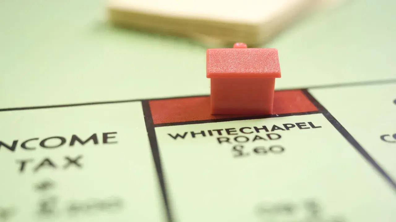 Une petite maison rouge sur le plateau Monopoly, près de Whitechapel Road. Le jeu simule le transfert de prêt.