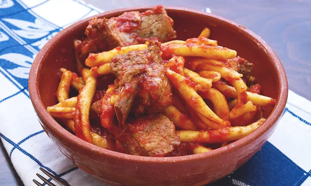 Piatto di pasta fresca con ragù di carne, un sapore autentico del cibo tipico calabrese in una ciotola di terracotta.