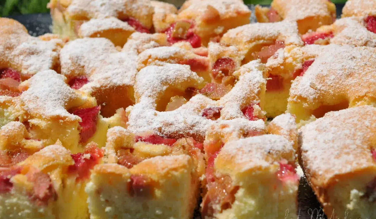 Szybkie ciasto z rabarbarem, posypane cukrem pudrem, wygląda apetycznie. Idealne na letnie popołudnie.