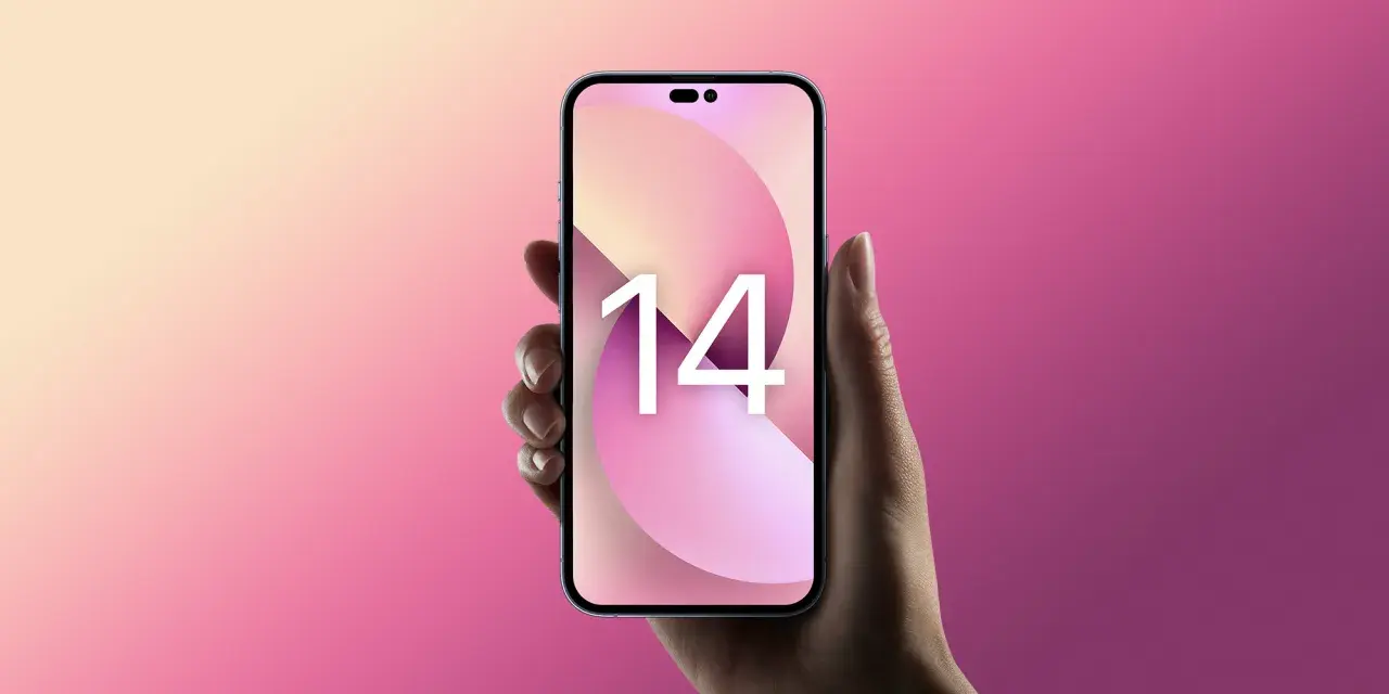 Dłoń trzyma różowy iPhone 14 z tapetą z cyfrą 14 na tle gradientu różu i beżu.