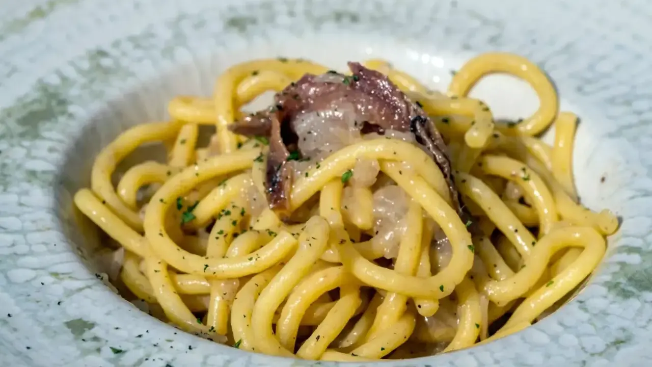 Un piatto di spaghetti con acciughe e prezzemolo, un'ottima idea per scoprire cosa mangiare a Padova.