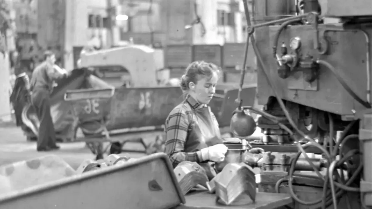 Kvinna arbetar vid maskin i fabriken, en del av arbetskraftsinvandring Sverige 1960.