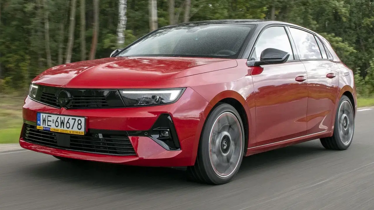 Czerwony Opel Astra Turbo pędzi leśną drogą.