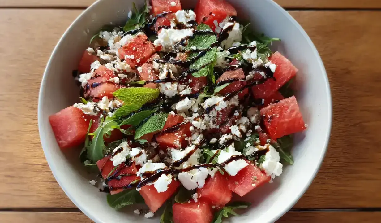 En uppfriskande sallad med tärnad vattenmelon, smulad fetaost och färsk basilika, ringlad med balsamvinäger.