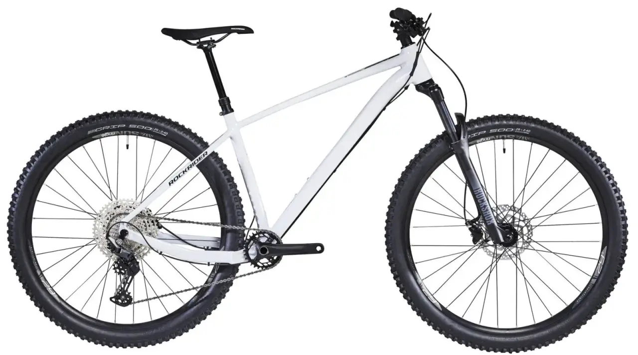 Biały rower hardtail z szerokimi oponami i amortyzatorem RockShox, gotowy na terenowe wyzwania.
