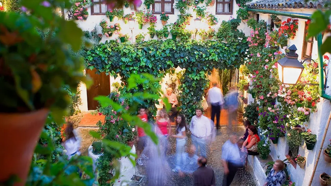 Blühende patios in Córdoba, mit Menschen, die durch den üppig begrünten Innenhof schlendern.