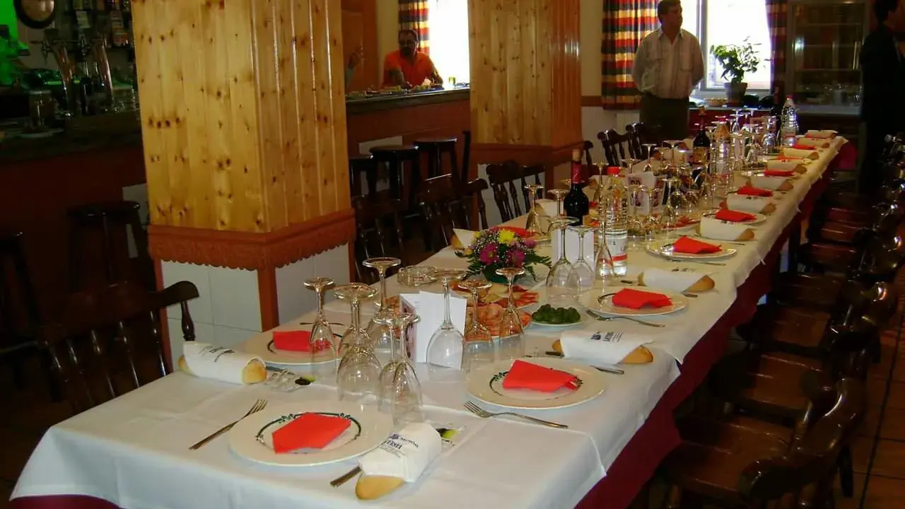 Mesa larga y elegante lista para comer en Riopar, con copas, platos y panecillos.
