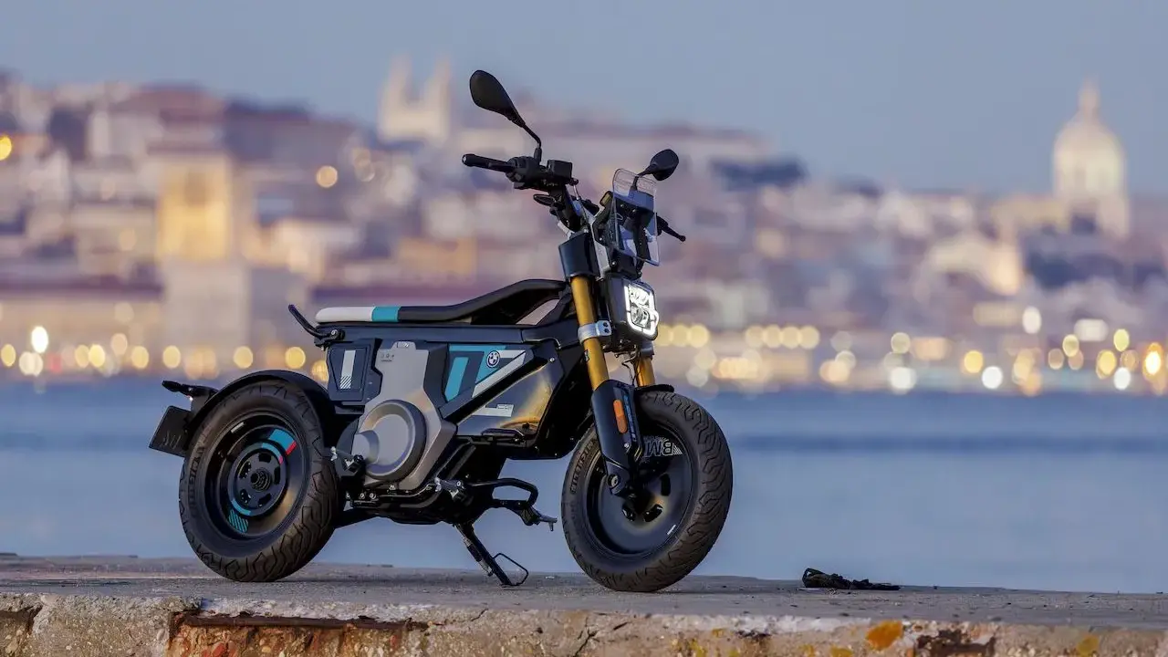Une trottinette électrique BMW futuriste, aux lignes audacieuses, se dresse sur un quai, la ville illuminée en arrière-plan.