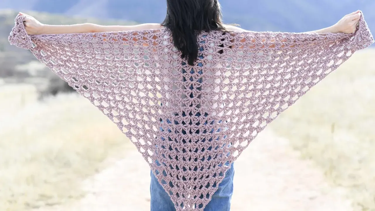 Chal triangular de crochet en tono rosa pálido, ideal para un patrón chal crochet facil.