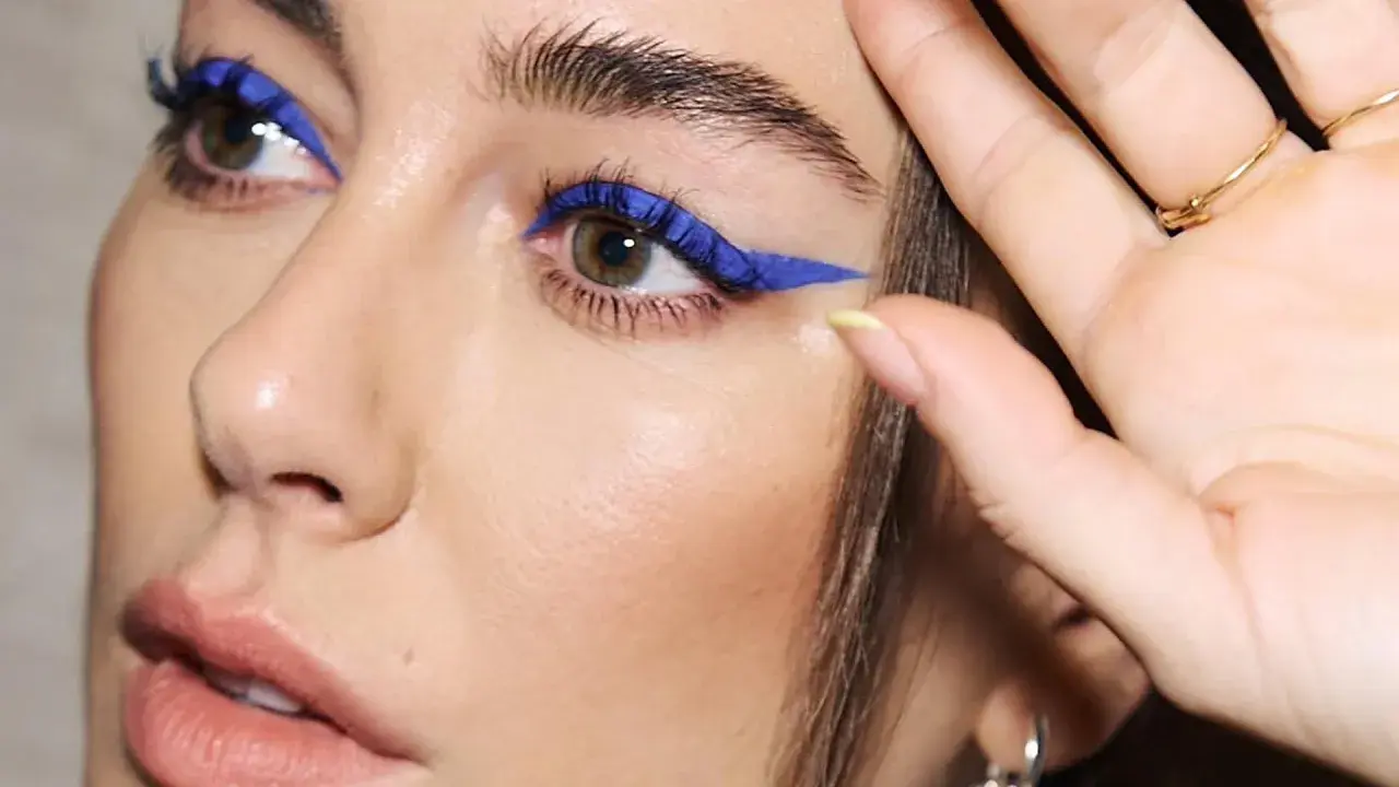 Ojos azules y piel blanca realzados con un audaz delineado azul eléctrico.