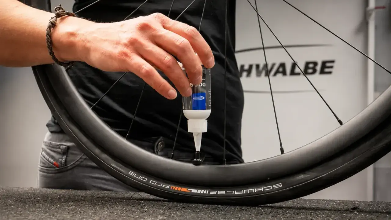 Eine Hand gibt Dichtmilch in den Fahrradschlauch eines Schwalbe Reifens.