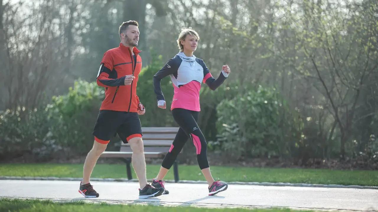 Ein Mann und eine Frau machen zügig **power walking** im Park.