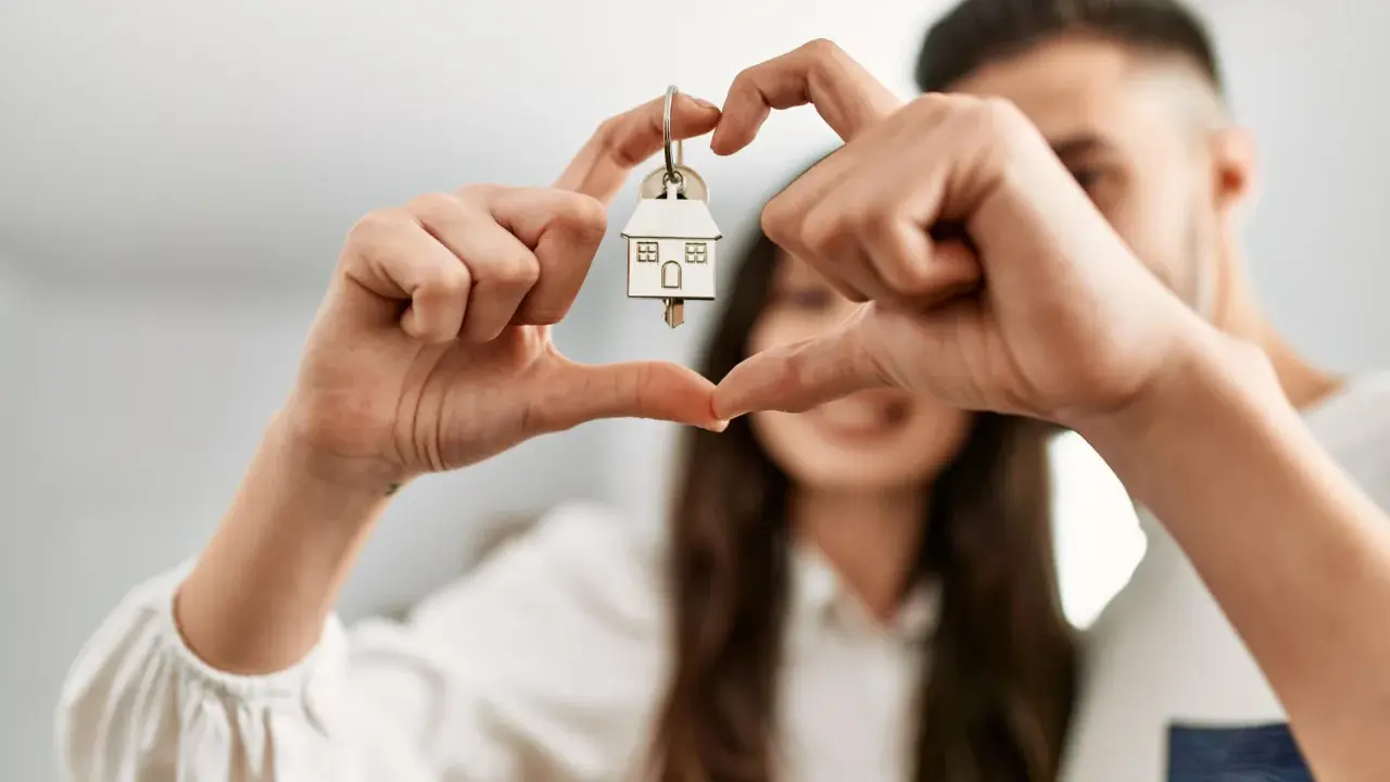 Un couple non marié célèbre son achat maison. Les mains forment un cœur autour de la clé, symbole de leur nouveau foyer, un nouveau départ après un décès.