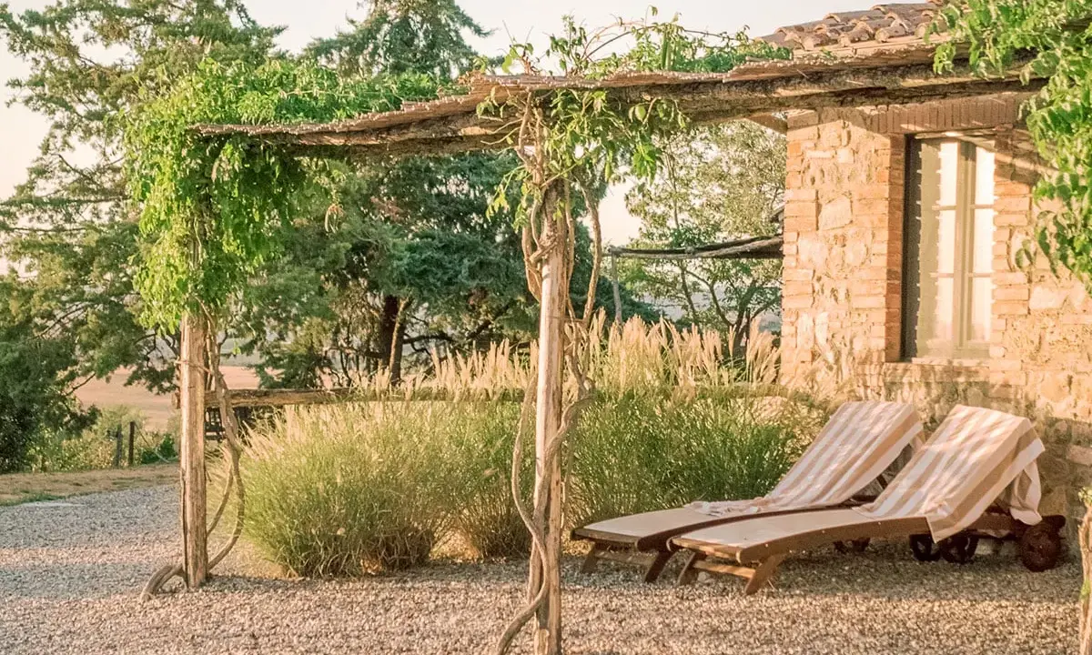 Due lettini prendisole sotto un pergolato fiorito, un'oasi di pace per il tuo itinerario Val d'Orcia.