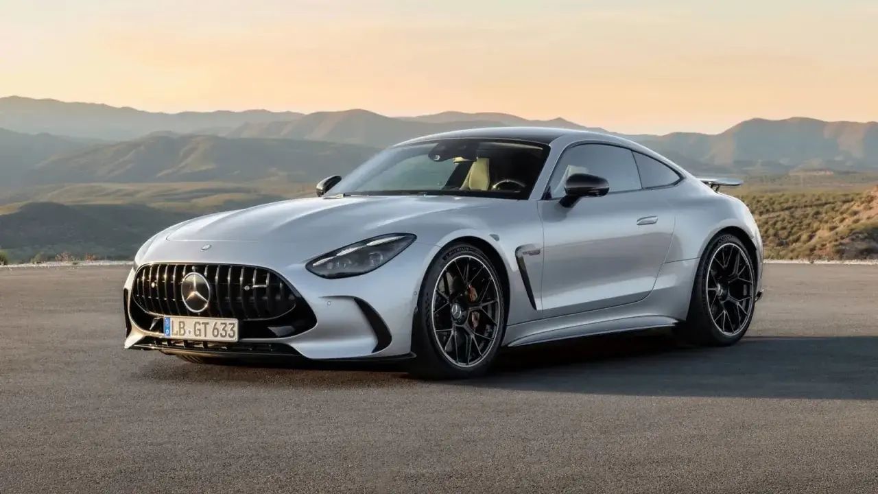 Un elegante Mercedes GTR plateado descansa en una carretera desierta, con montañas onduladas al atardecer de fondo.