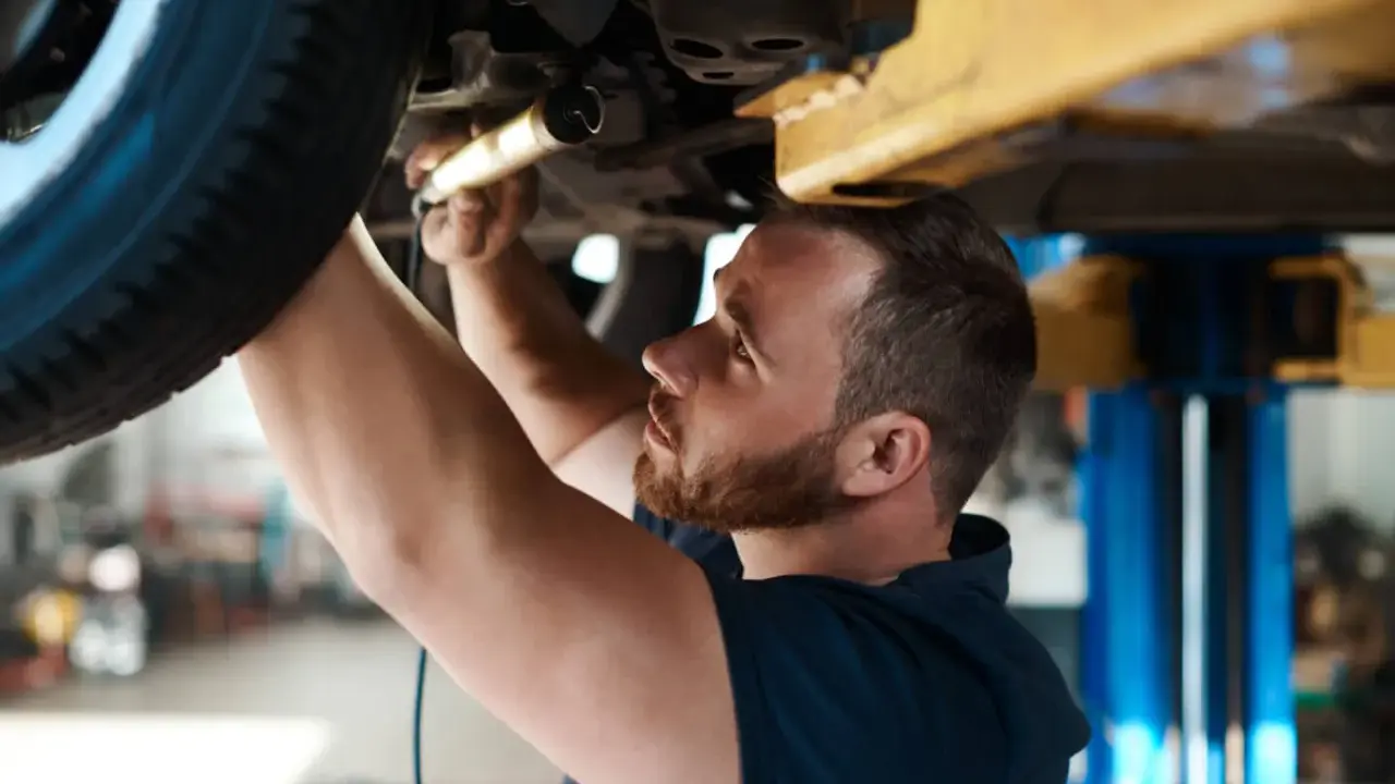 Mechanik sprawdza zawieszenie auta na podnośniku. Dowiedz się, ile kosztuje sprawdzenie zawieszenia na stacji diagnostycznej.