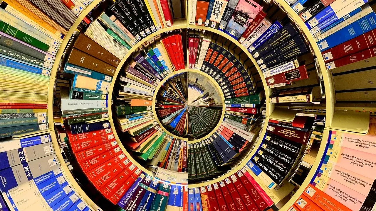Książki ułożone w spiralę, tworząc piotr kościelny dom wiedzy. Widać tytuły o naukach ścisłych i przyrodniczych.