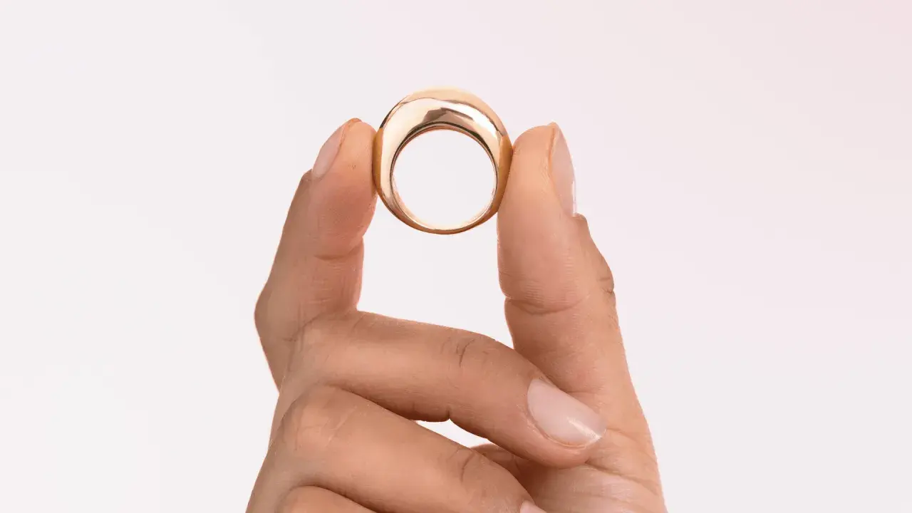 Dita che mostrano un anello in oro 18k 0.750, un gioiello elegante e moderno.
