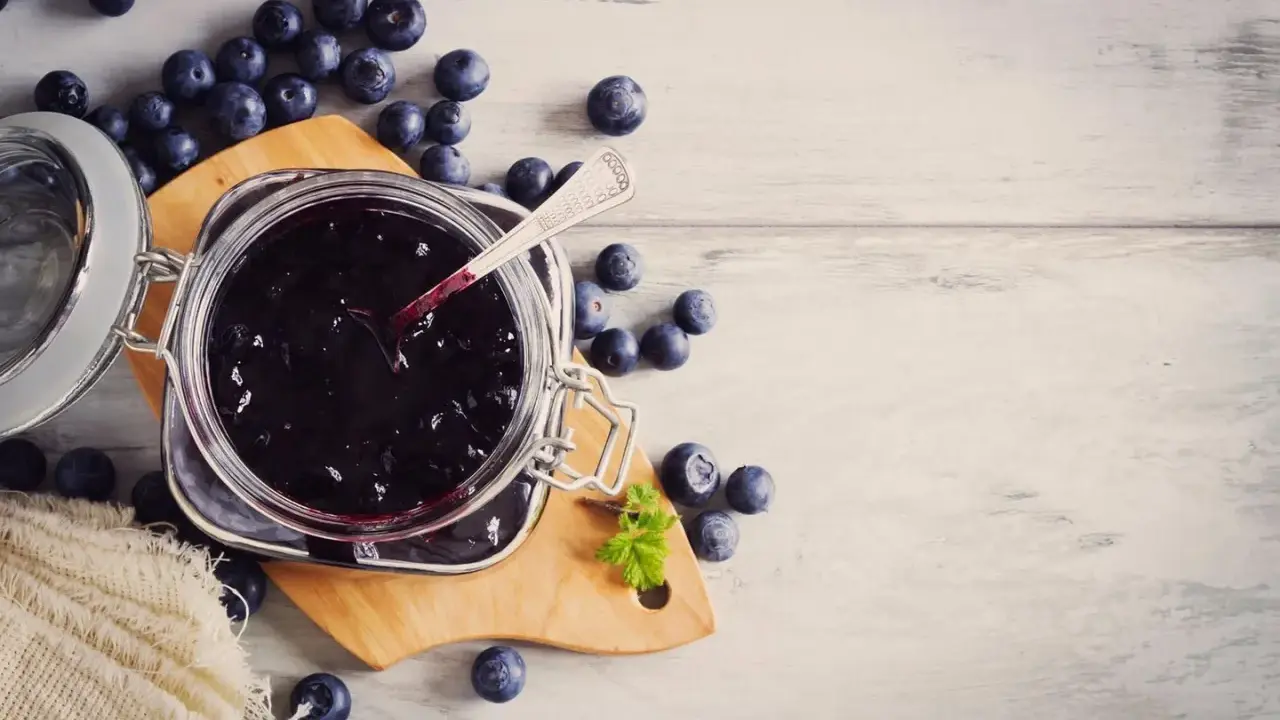Frische Heidelbeeren und selbstgemachte Heidelbeermarmelade im Glas, bereit zum Genießen.