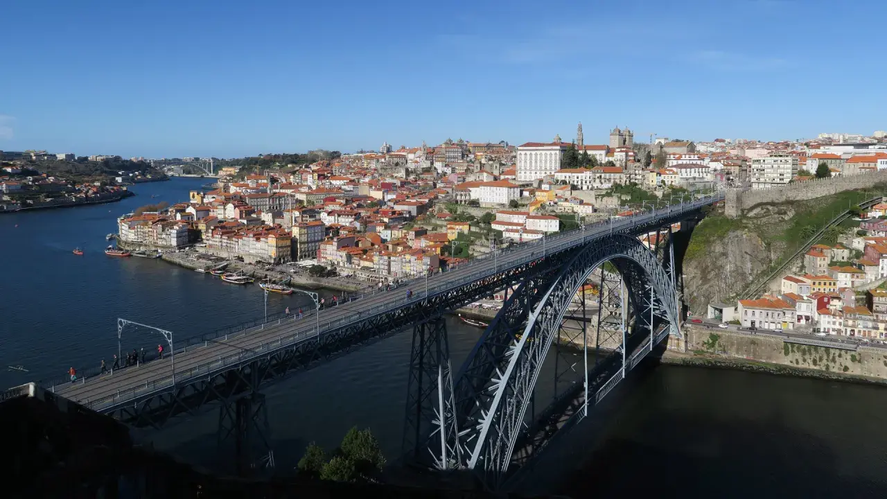 El icónico puente de Oporto cruza el río Duero, conectando la ciudad con sus coloridas casas y barcos turísticos.