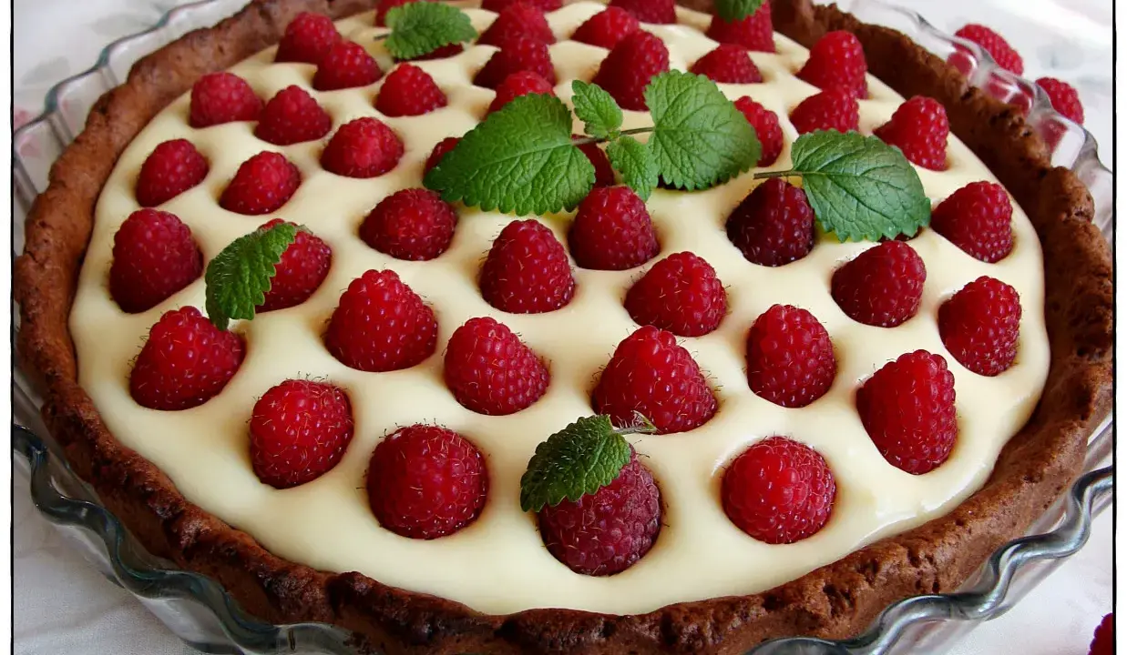 Tarta z mascarpone i białą czekoladą, ozdobiona malinami i miętą. Pyszny deser na każdą okazję.