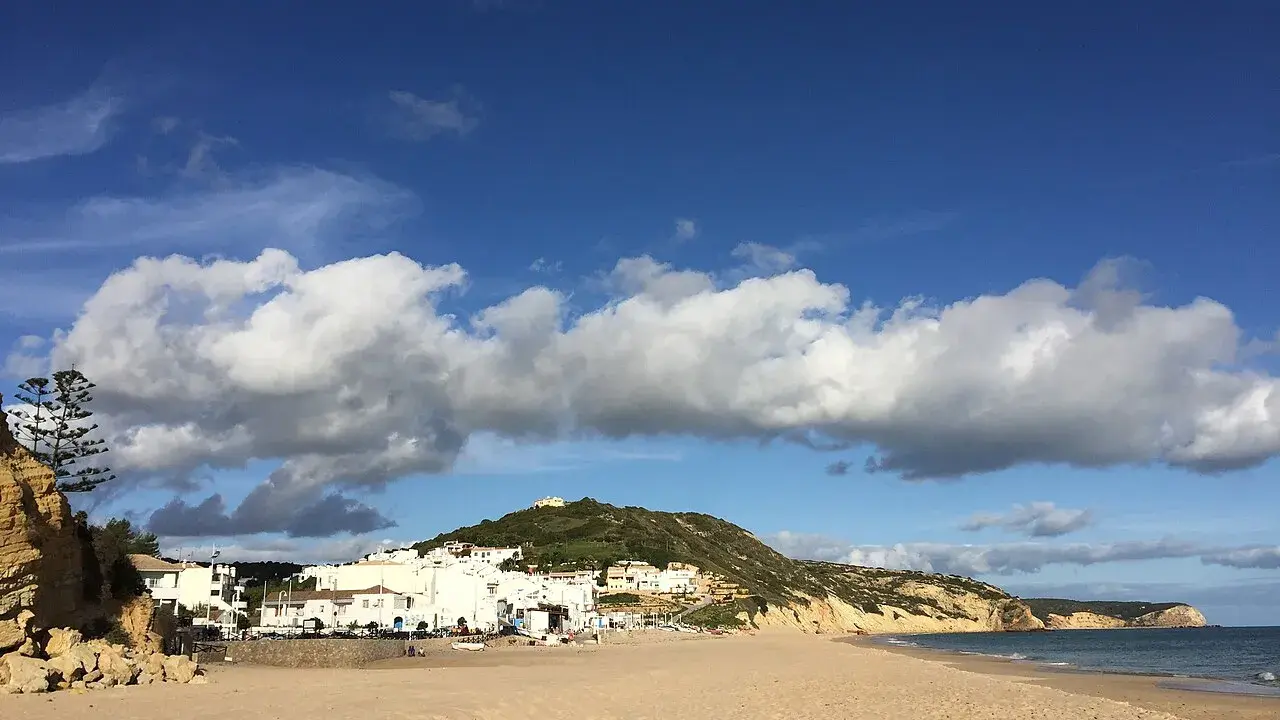 Sonne, Sand und weiße Häuser: Ein malerischer Blick auf Salema, Portugal, mit dem Atlantik und dramatischen Wolken.