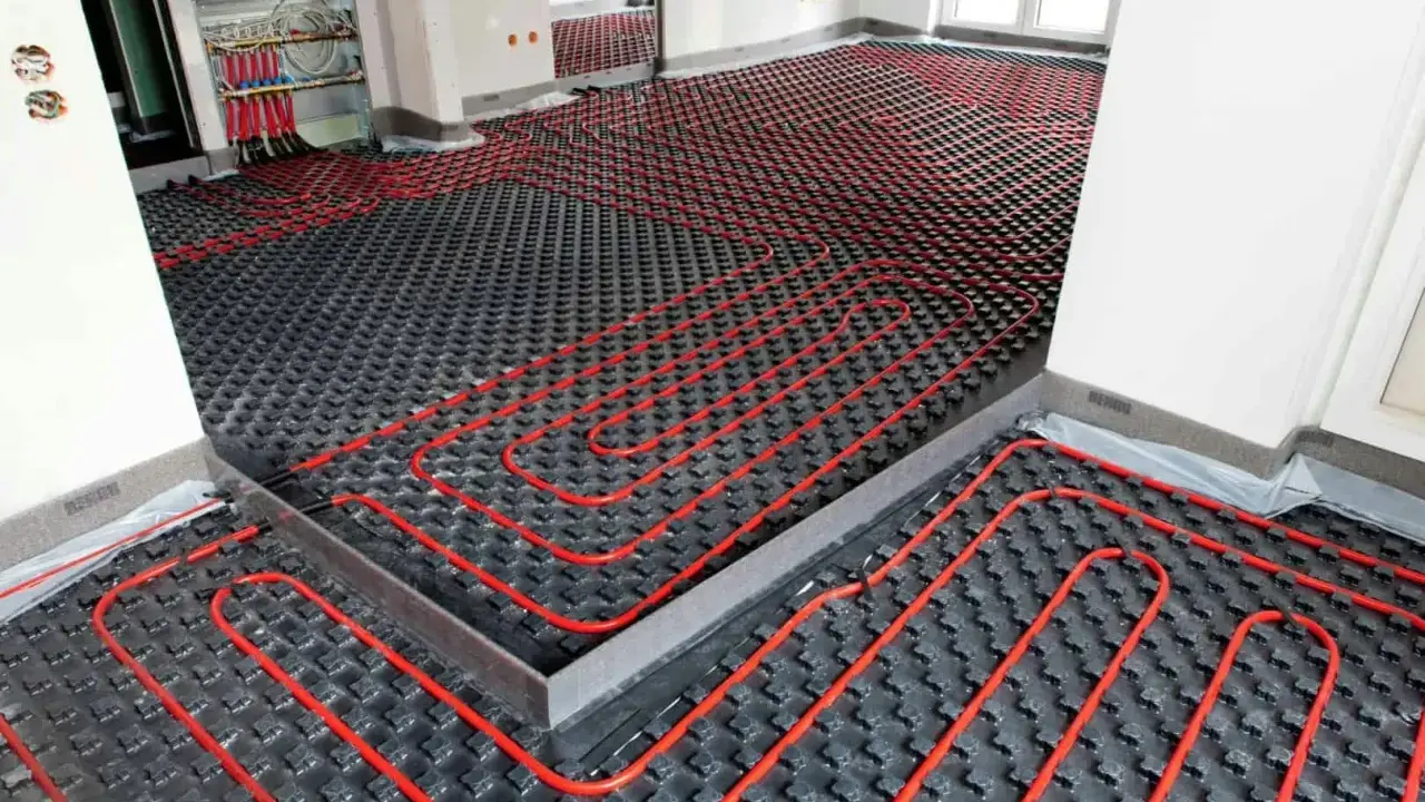 Instalación de suelo radiante con tuberías rojas sobre paneles negros, preparado para aerotermia.
