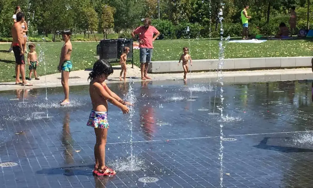 Niños y adultos disfrutan del agua en las fuentes del madrid rio parque.