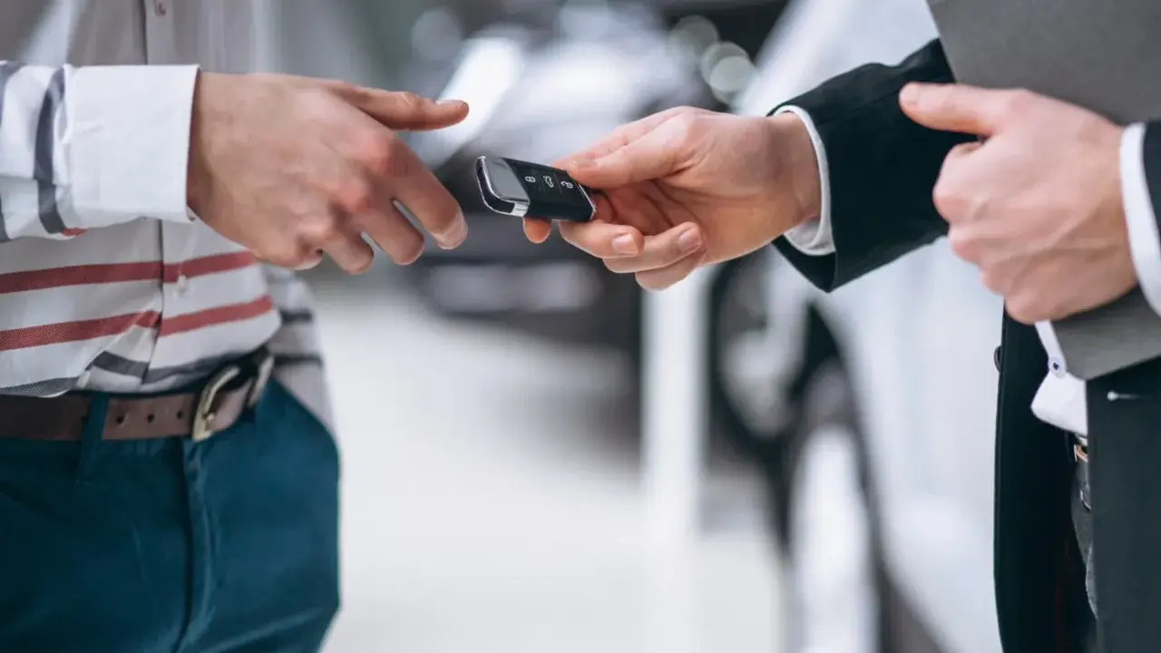 Un hombre entrega las llaves de un coche para una tasación de vehículo.