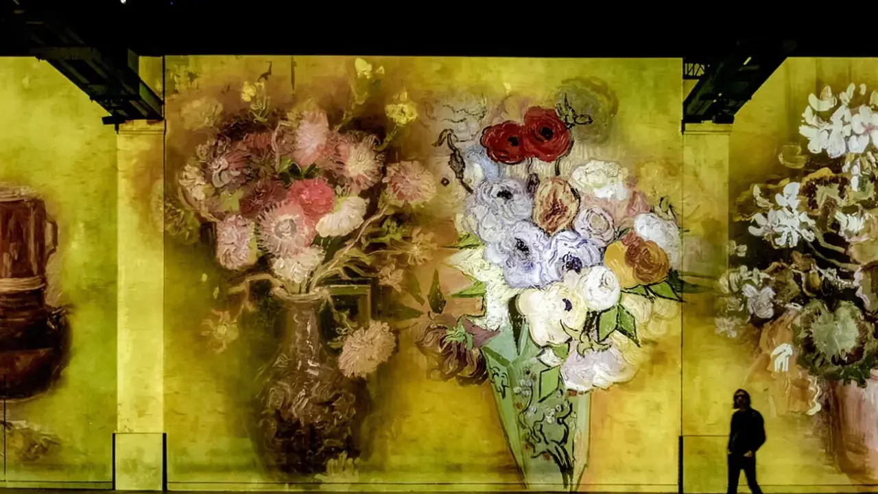 En person går förbi en väggprojektion av Van Goghs blomsterbuketter, en hyllning till hans tid i Paris.