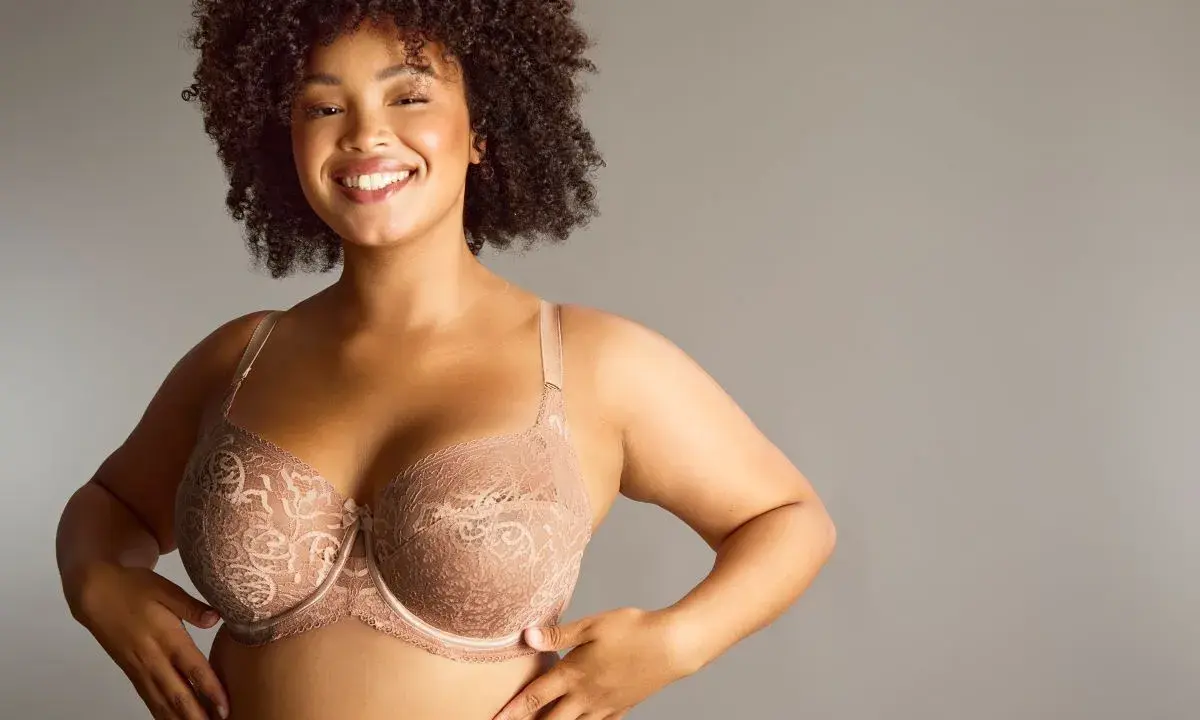 Donna sorridente con tette grandi perfette in reggiseno di pizzo color carne.