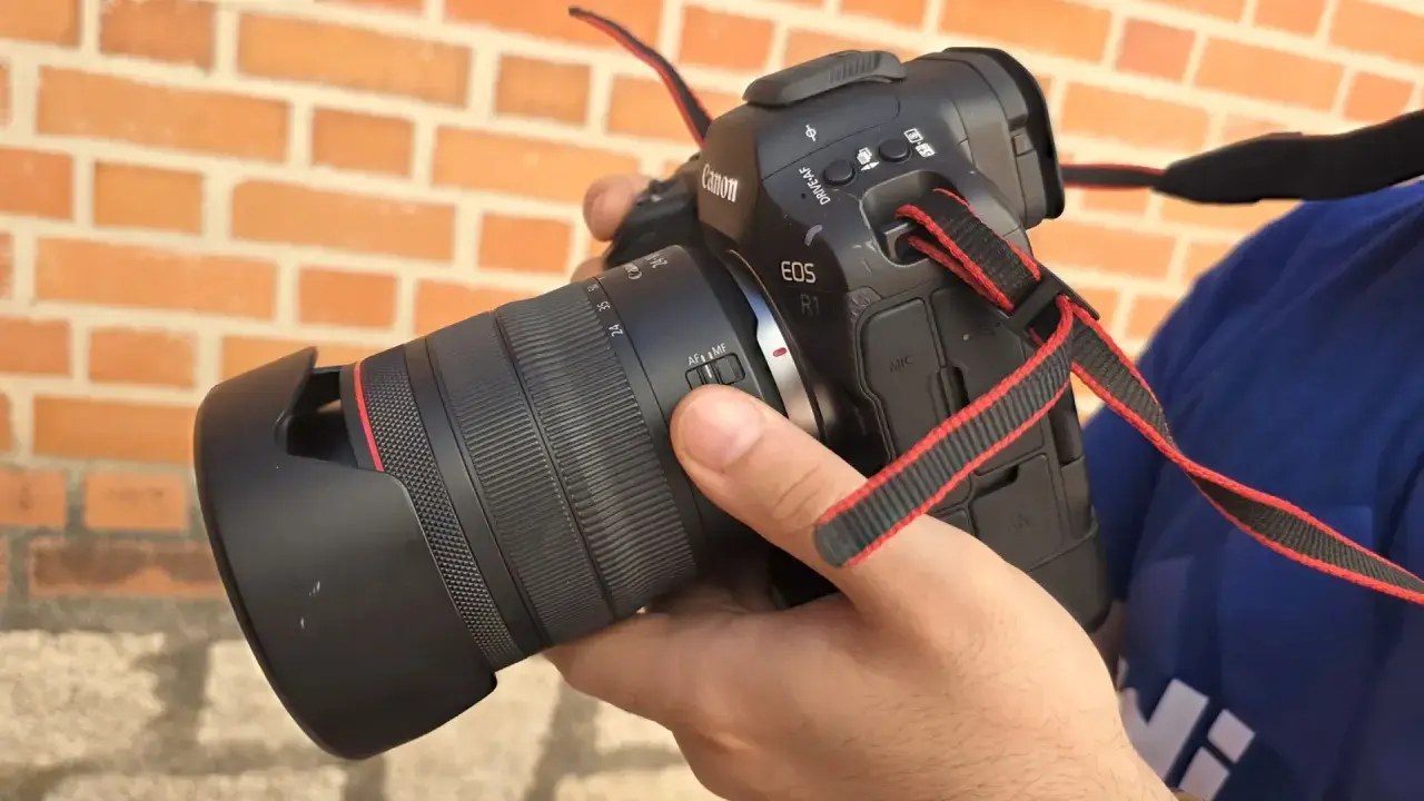 Mano sosteniendo una cámara Canon R1 con lente, lista para capturar momentos.